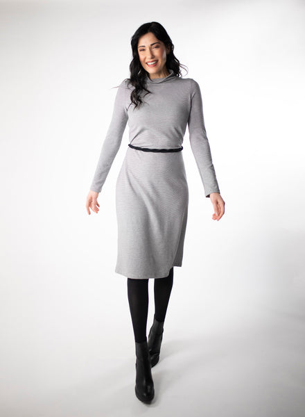Grey and white striped dress with full length sleeve and mock neck. Black belt around waist with black tights and heels.