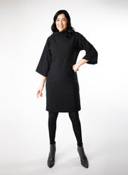 Black knee length Bamboo fleece sweater dress with full sleeves and wide mock neck collar. Styled with black leggings.