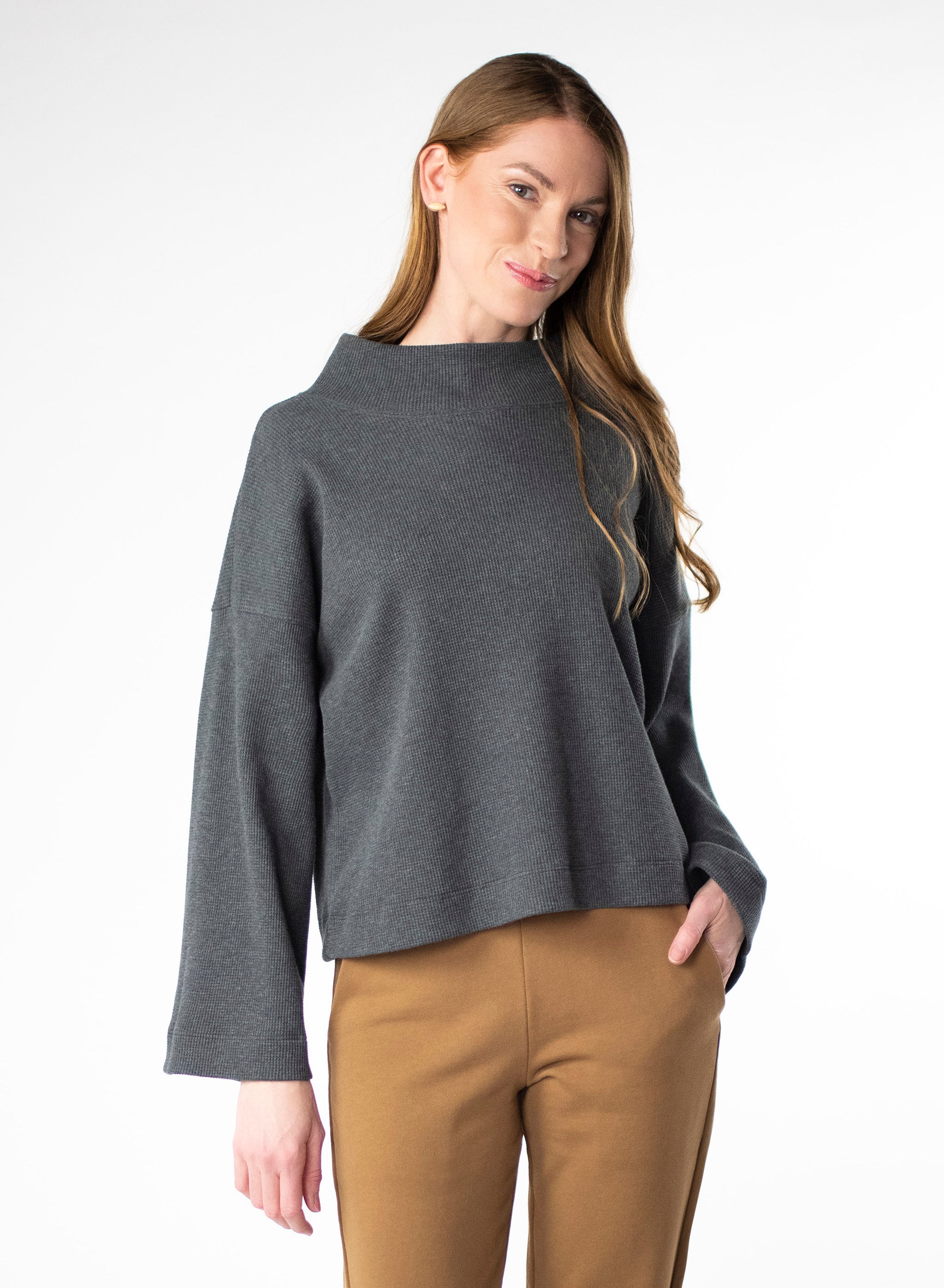 Charcoal waffle knit cropped sweater. Wide mock neck style neckband and full sleeves. Styled with Nutmeg trousers.