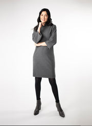 Charcoal Grey knee length Bamboo fleece sweater dress with full sleeves and wide mock neck collar. Styled with black leggings. 