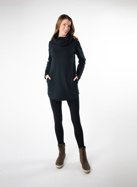 Black organic cotton fleece sweater with side seam pockets and a fitted hood. Reverse fabric details on seams and curved hem. Styled with Black leggings. 