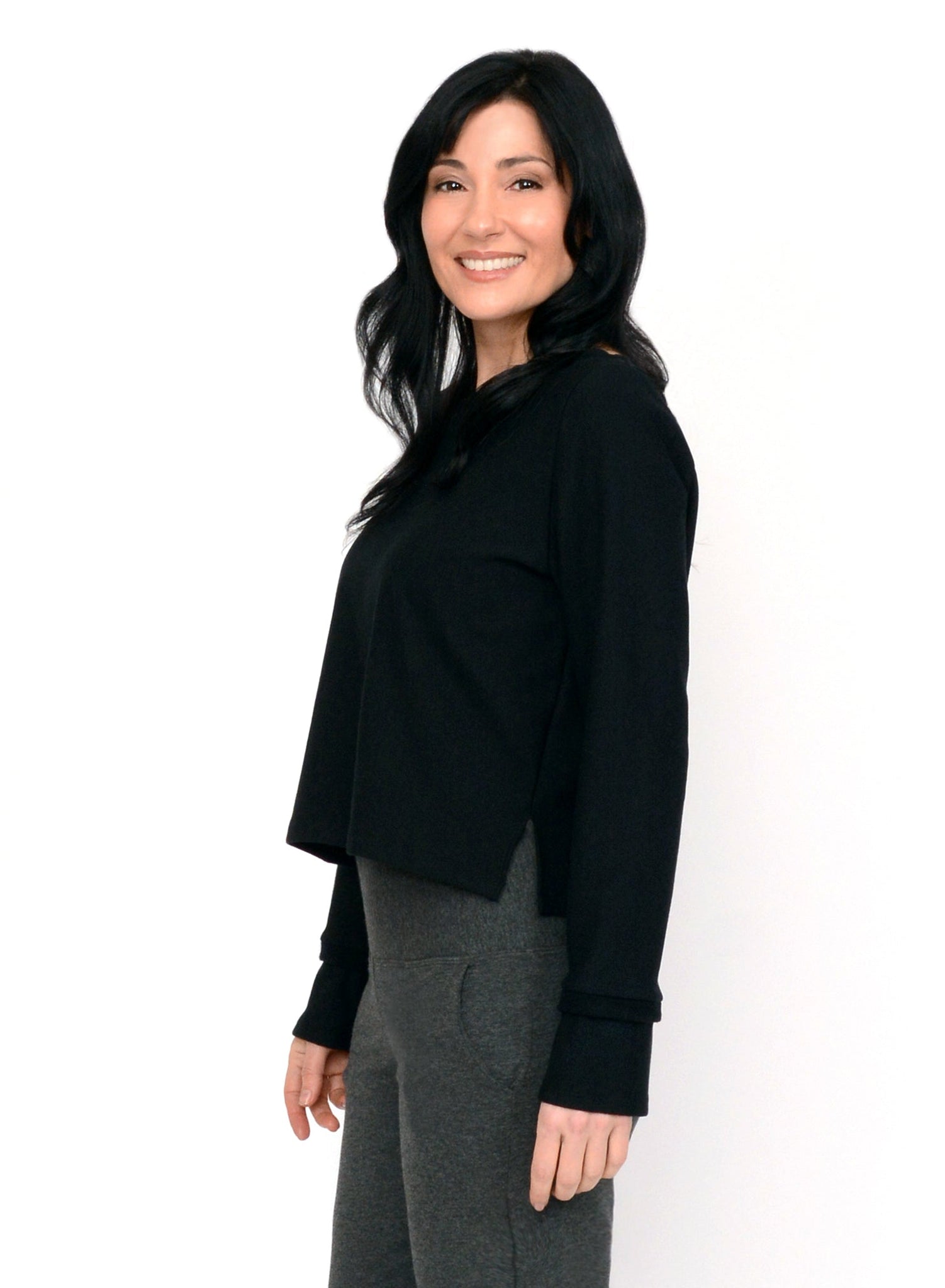 Black Bamboo fleece cropped sweater with pleat at shoulder seam and reverse fabric detail on cuff. Styled with charcoal grey pants. 